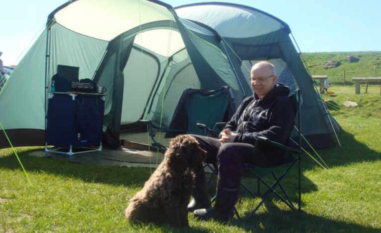 Man and his dog sitting next to his tent